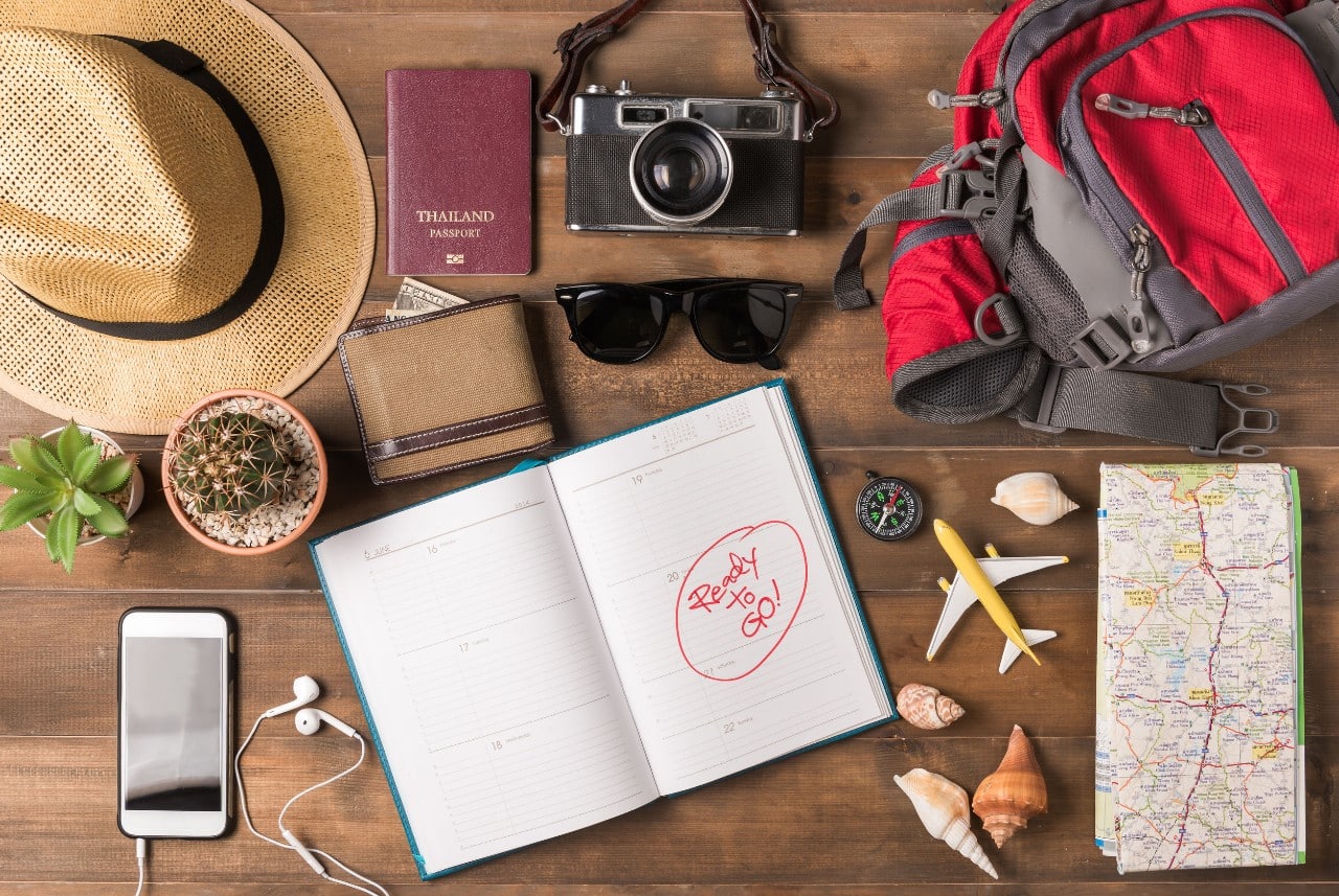 table of travel items, maps, brochures, camera, sunhat; vacation request concept