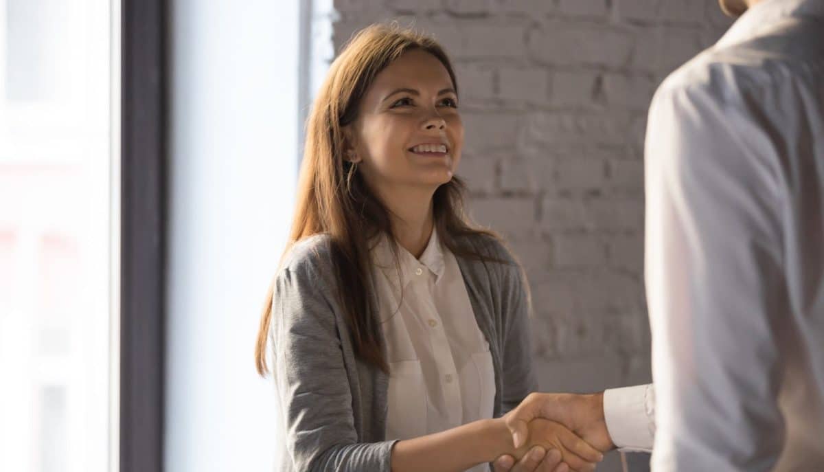 Businessman shake hand of excited female employee greeting with job promotion or employment, male boss handshake happy young woman worker congratulating with success or achievement in office