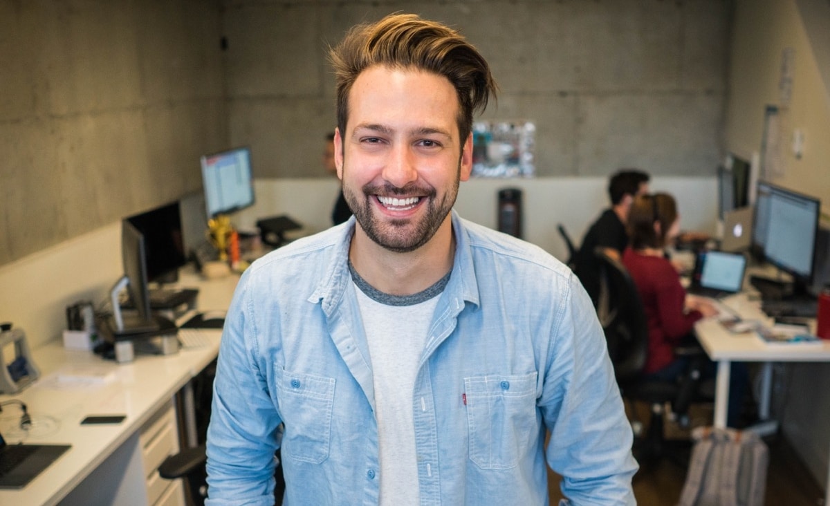 young worker in an office smiling at the camera; retaining tech talent concept