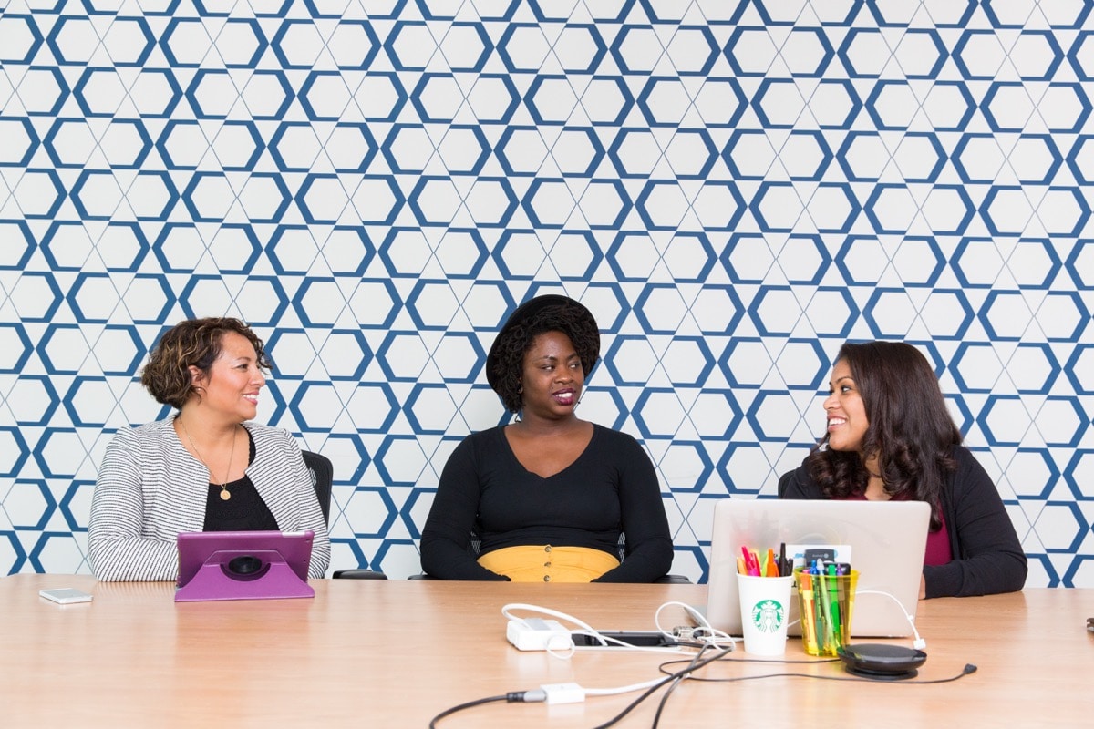 Three businesswomen meeting in a colorful conference room; employer branding experts concept