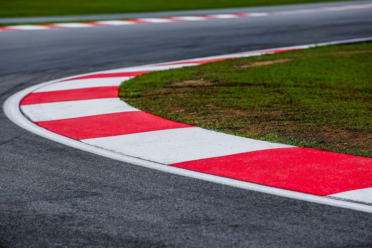 Curving asphalt red and white curb of a race track; digital transformation in banking concept