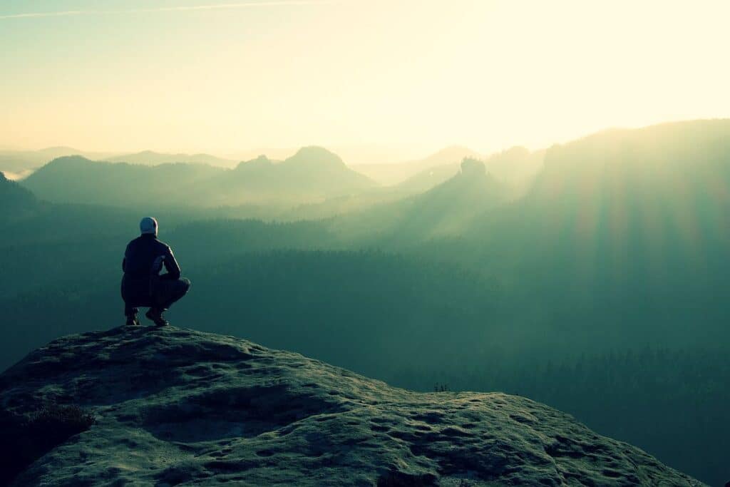 Hiker sits on a rocky peak; lifelong learning concept