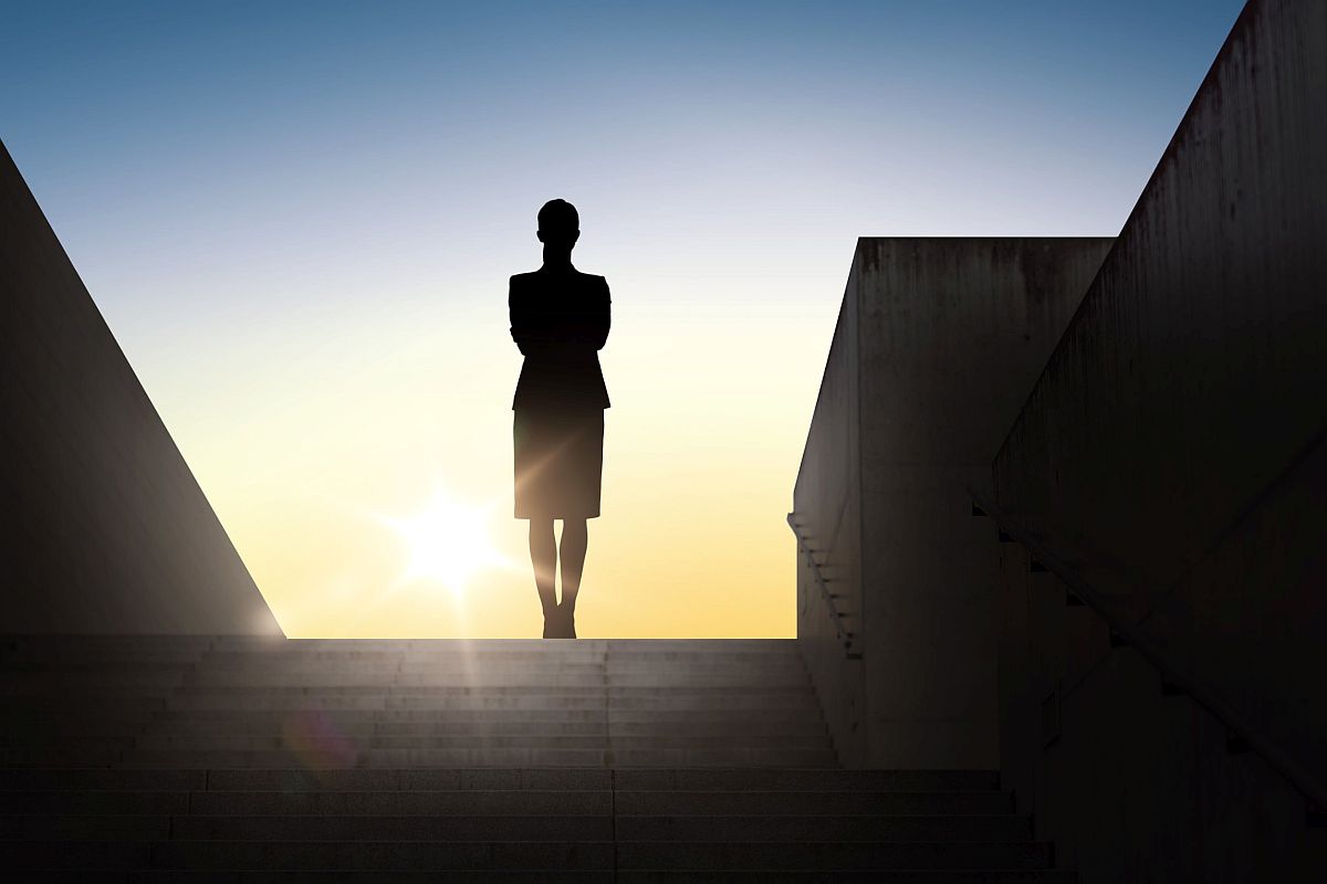 silhouette of a businesswoman facing the sunrise; motherhood penalty concept