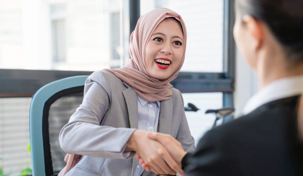 A Muslim young businesswoman is happy about the deal. They shake their hands to celebrate their good partnership.