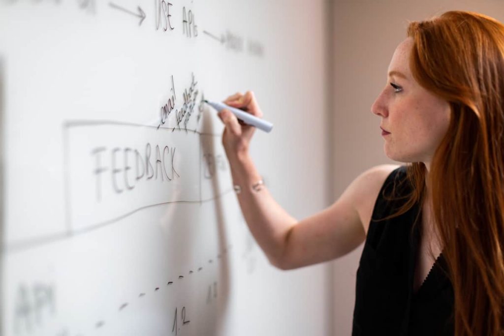 business woman using marker on whiteboard; pandemic impact, dev jobs concept