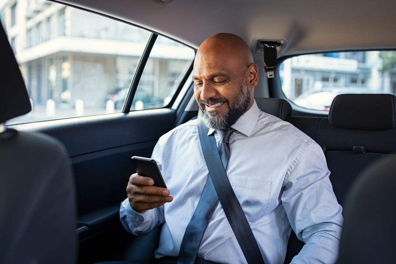 businessperson using a smartphone in the backseat of a car; CHRO-CEO partnerships concept
