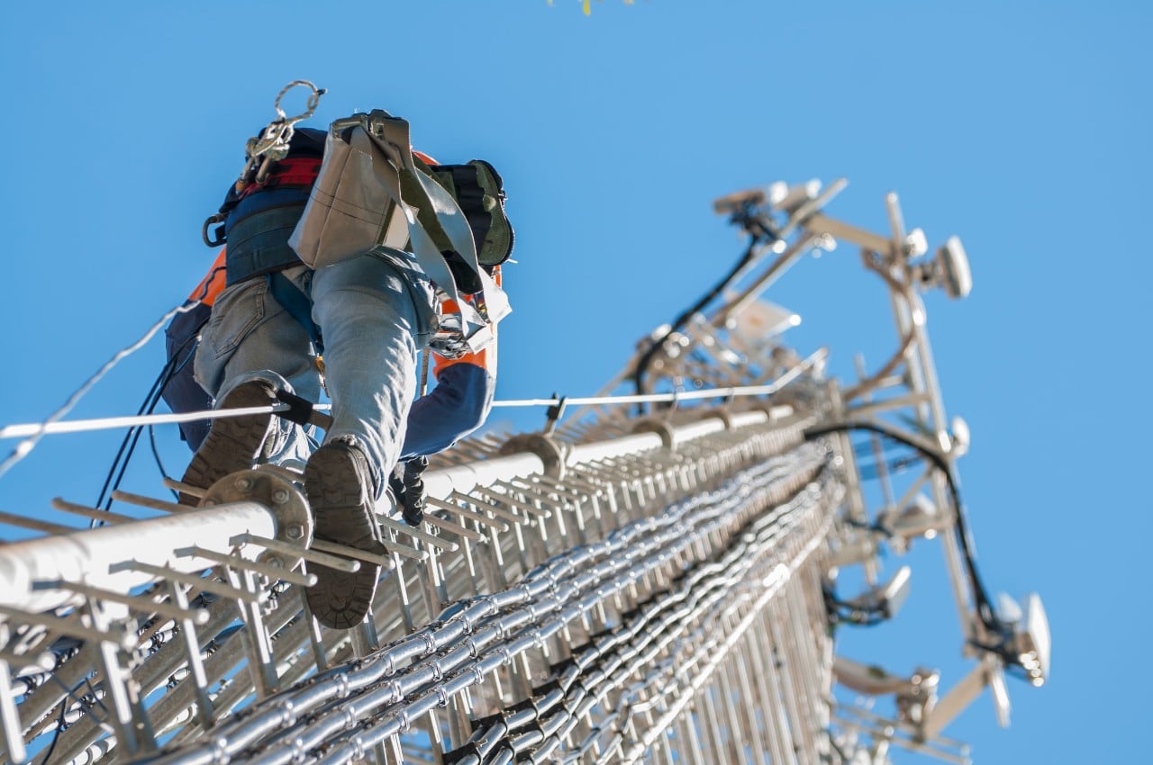 worker climbing a cellphone tower; talent management in telecom concept