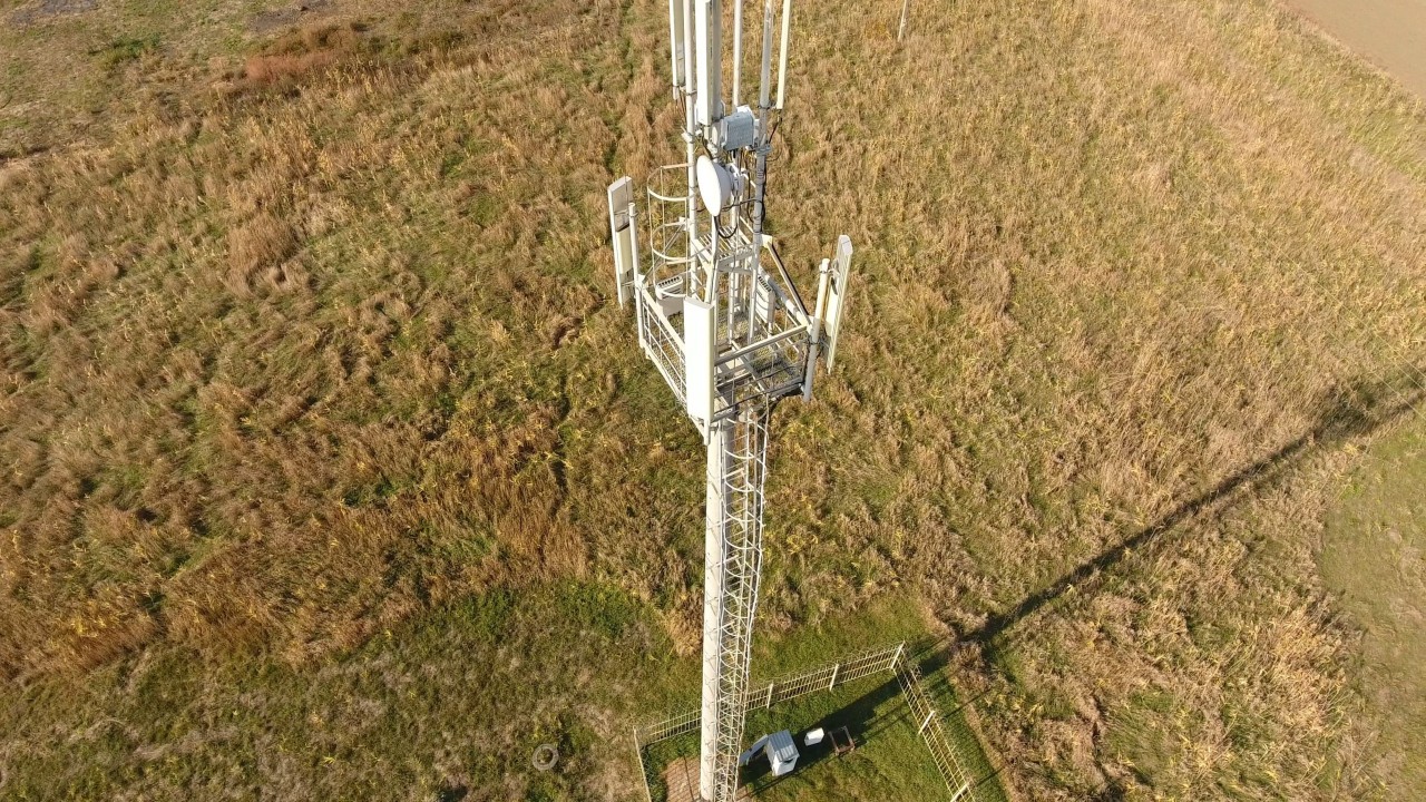 dramatic overhead shot of a 5G tower on a green landscape; talent management in telecom concept